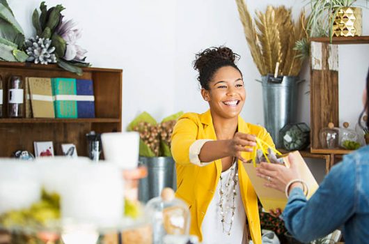 Saleswoman (16-17 years, mixed race African American) helping customer.